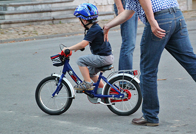 Vater bringt Sohn das Fahrradfahren bei, Anschupser